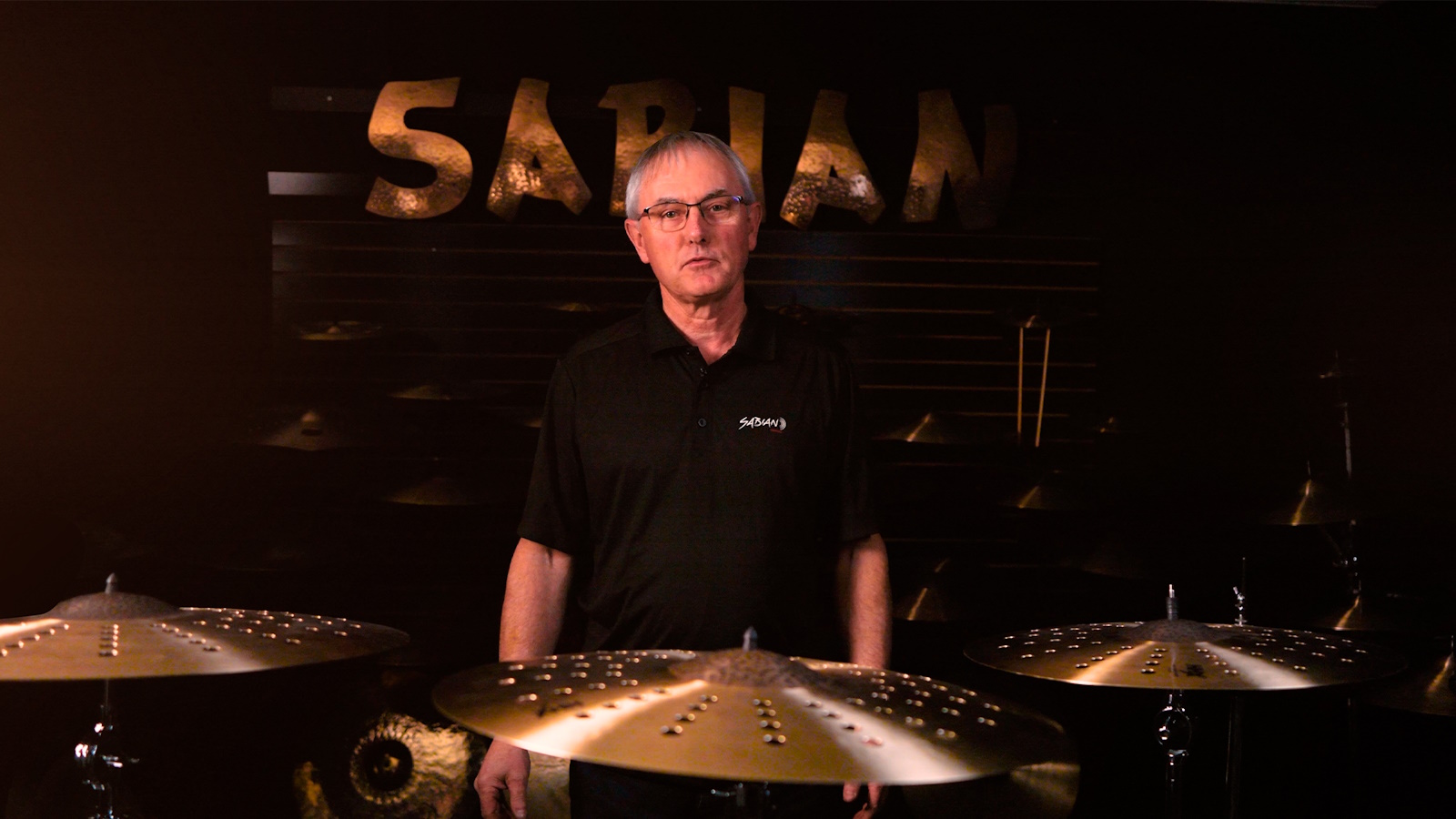 3. Mark Love stands behind three cymbal stands with three HHX Complex cymbals